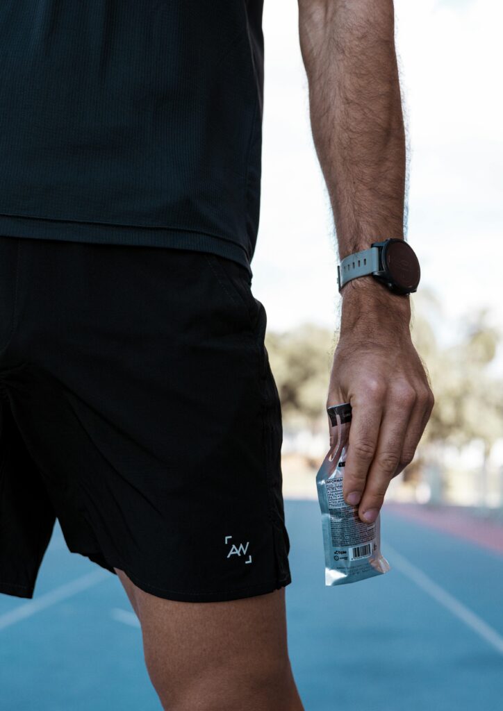 Close-up of male athlete holding energy gel on outdoor track. Fitness and sports-focused lifestyle.